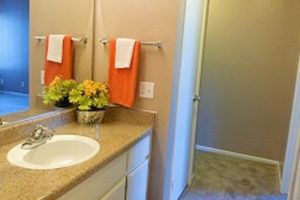 large bathroom sink with mirror, orange towel, yellow and green flowers