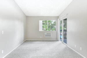 Interior Living room, Neutral gray carpeting, sliding glass door to balcony, neutral toned walls.