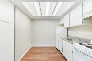 Interior Unit Kitchen, Linoleum countertop, wood floors, white appliances, white cabinetry, stainless steel sink.