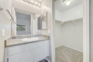 Interior Unit Bathroom, white cabinets, large vanity mirror, attached walk in closet.