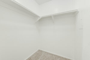 Interior Unit Closet, white walls and shelving, neutral toned carpeting.