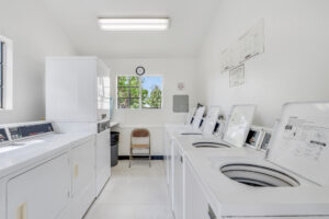 Interior Laundry Facilities, white walls, tile floors, 4 washing machines, 4 dryers.