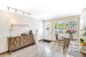 Interior Leasing Office, rustic decor, white walls with wood floors, avanath signage on wall, coffee station and water tank, round table with brochures.